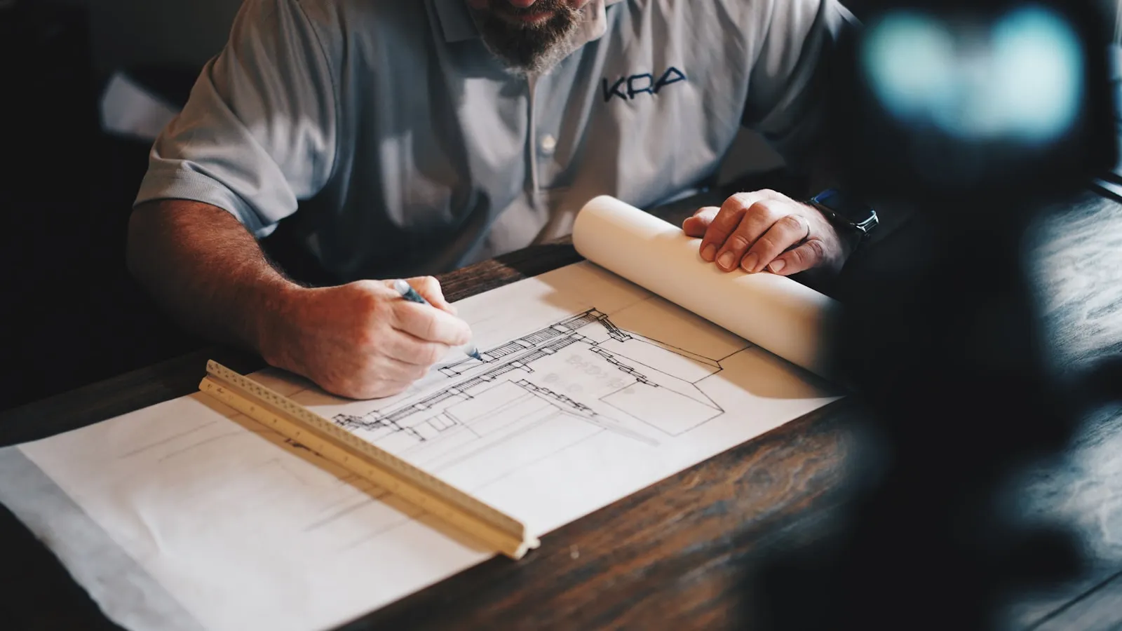 James Hartley pencilling a joinery drawing onto paper across the bench